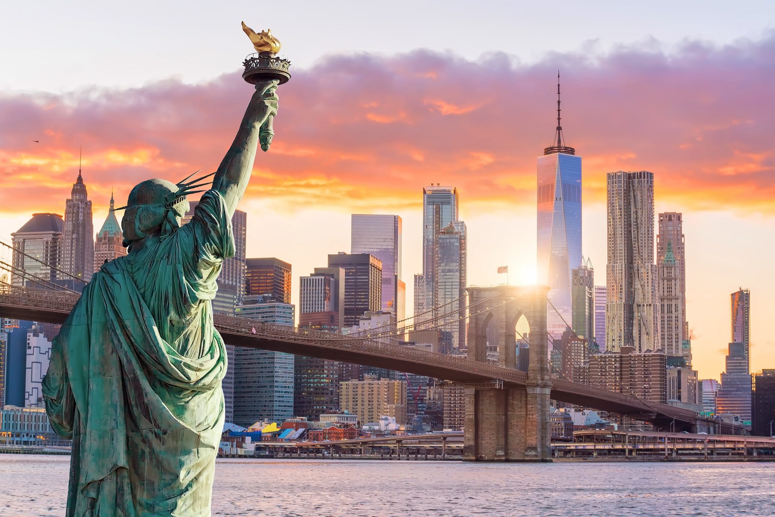 Statue Liberty and New York city skyline at sunset.