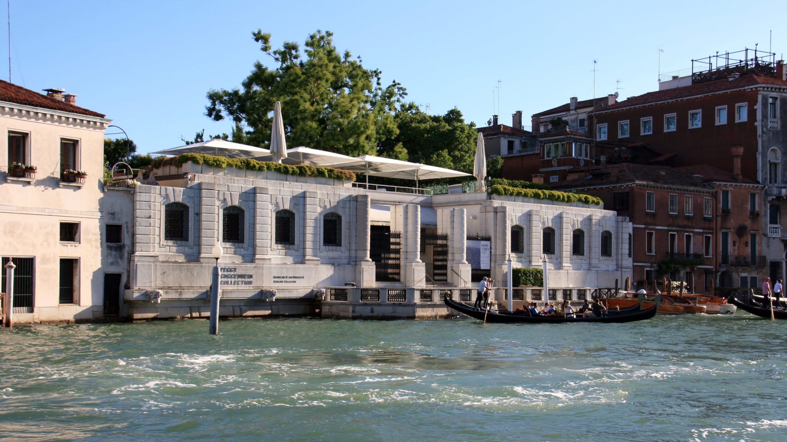 The exterior of a white palazzo building with a waterfront terrace, which houses the museum.