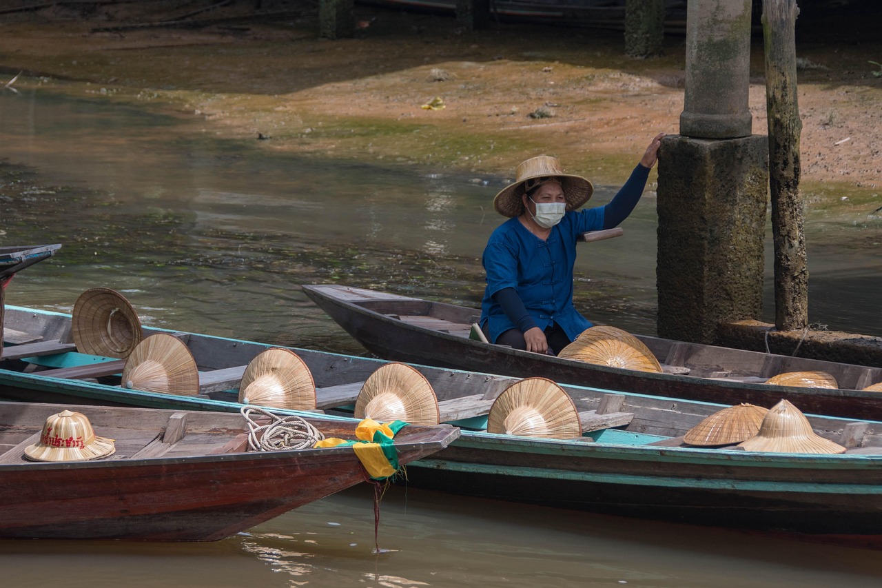 Family boarding a long-tail boat at a sunny floating market in Bangkok